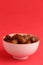 Vertical shot of a bowl of dates on a crimson background