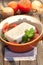 Vertical shot of a bowl of greek salad with tomatoes, basil, onion and feta cheese on a wooden table