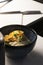 Vertical shot of a bowl of noodle and vegetables on a white table