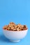 Vertical shot of a bowl of nuts on a blue background