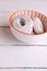 Vertical shot of a bowl of powdered sugar donuts on white background