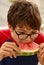 Vertical shot of a boy biting into a slice of watermelon