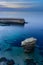 Vertical shot of a breathtaking blue and clear sea with a stone fence