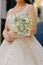 Vertical shot of a bride holding a stunning white rose bouquet