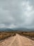 Vertical shot of a brown road leading to distant misty hills