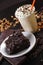 Vertical shot of a brownie with chocolate chips next to cappuccino with whipped cream