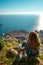 Vertical shot of a brunette girl sitting on top of the srd mountain looking down at the ancient Croatian city of Dubrovnik. Warm