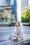 Vertical shot of businesswoman in beige suit, sitting alone in city centre, waiting near office building