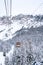Vertical shot of a cableway ski lift closed cabin in snow-covered forested mountains