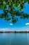 Vertical shot of a calm water surface with a skyline of Mainz, Germany seen through tree branches