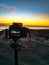 Vertical shot of a camera on a tripod placed on a shore and photographing the sunset at a beach