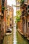 Vertical shot of a canal in Venice, Italy with boats and old houses