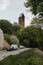 Vertical shot of cars parked on a quaint country road near an ancient clock tower