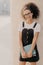 Vertical shot of cheerful young Afro student carries notepads or diary, wears white t shirt, black sarafan, ready for having