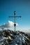 Vertical shot of a Christian metal cross standing on the rock with a flag