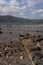 Vertical shot of the coast of an ocean filled with rocks, surrounded by hills