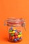 Vertical shot of a colorful candy coated chocolate peanut in a glass jar