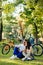 Vertical shot of a concentrated pensive couple of bicyclists having rest in the park, sitting on a lawn and looking far ahead. A