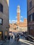 Vertical shot of a crowded narrow street leading to the square of Piazza del Campo in Siena, Italy