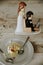 Vertical shot of a cute figurine with groom and bride by a plate of cake on a wooden table