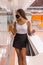 Vertical shot of a cute, Hispanic girl at the mall for Black Friday with lots of shopping bags