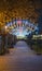 Vertical shot of a decorated archway, surrounded by lush trees, adorned with magical fairy lights