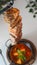 Vertical shot of a delicious barbeque hanging over a bowl of soup