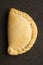 Vertical shot of a delicious empanada isolated on a black surface