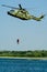 Vertical shot of a diver hanging on a rope of a military helicopter above the river