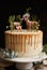 Vertical shot of a dreamy cake with white cream and orange drip with a forest and reindeers on top