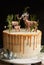 Vertical shot of a dreamy cake with white cream and orange drip with a forest and reindeers on top