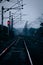 Vertical shot of an eerie railway scenery with two people walking in the distance
