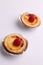 Vertical shot of egg tarts with raspberries on top isolated on a white background