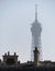 Vertical shot of the Eiffel Tower over the roofs of Paris shadowed by fog