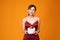 Vertical shot of an elegant woman in a red dress carrying a birthday cake