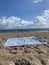 Vertical shot of an empty towel on a sandy beach with a calm seascape view at daytime