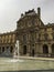 Vertical shot of the facade of the Louvre Museum and a fountain in front of it in Paris, France