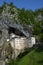 Vertical shot of the famous Predjama Castle in Slovenia with tall rocks above it on a vibrant field