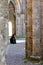 Vertical shot of a female sitting on the ground in Abbey of San Galgano under the sunlight in Italy