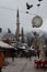 Vertical shot of a flock of pigeons taking flight from a busy market in Sarajevo