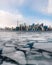 Vertical shot of the frozen river with tall buildings of Toronto in the background, Canada