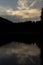 Vertical shot of Fusine Lakes with the reflection of the pine trees of the background in Italy