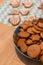 Vertical shot of gingerbread cookies in a bowl, with decorated ones in the background