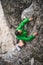 Vertical shot of a girl in a green coat climbing cliffs