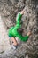 Vertical shot of a girl in a green coat climbing cliffs