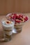 Vertical shot of a glass bowl of vanilla yogurt with currants on top on a beige background