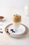 Vertical shot of a glass of Dalgona coffee on saucers with coffee beans on it on the table