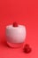 Vertical shot of a glass of liquid raspberry yogurt isolated on a red background