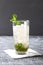 Vertical shot of glass of mint julep.Served alcohol drink on the white napkin.Grey table and gray wall
