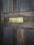 Vertical shot of a golden mail slot on a weathered wooden door